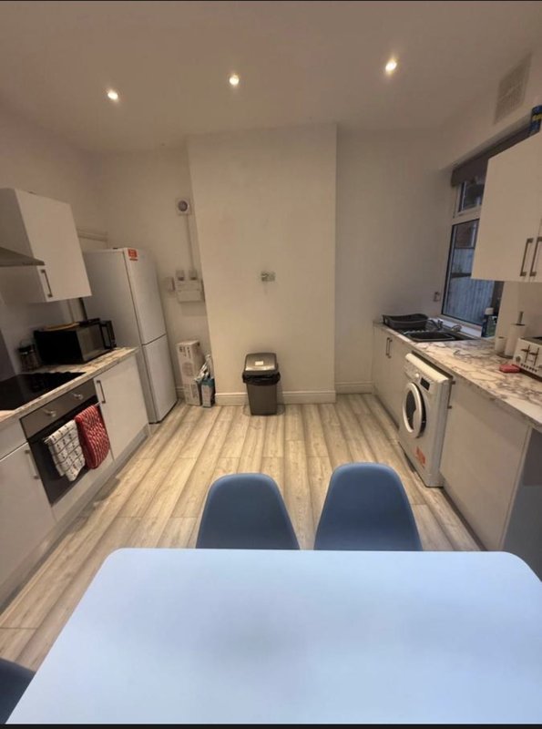 Modern kitchen with white units, stainless steel appliances, wooden flooring and dining table