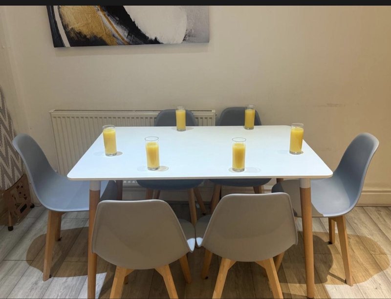 Dining table with six chairs and yellow candles, wooden floor and radiator