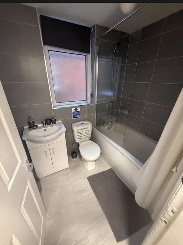 Modern bathroom with white vanity, toilet, shower enclosure and window