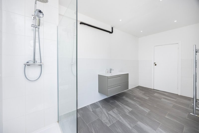 Modern bathroom with walk-in shower, grey wood-effect flooring, vanity unit and white tiles