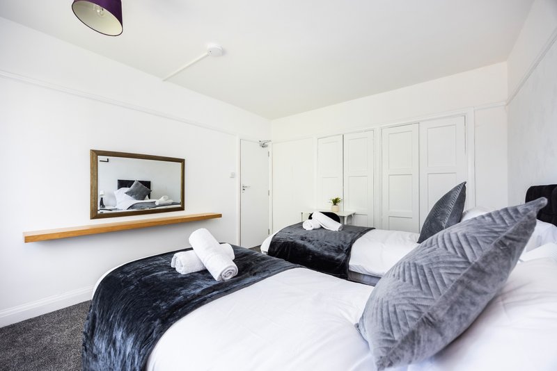 Modern bedroom with two single beds, white bedding, black throws and patterned cushions