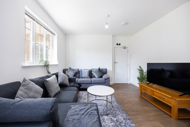 Modern living room with dark grey corner sofa, cushions, white coffee table and wooden TV stand