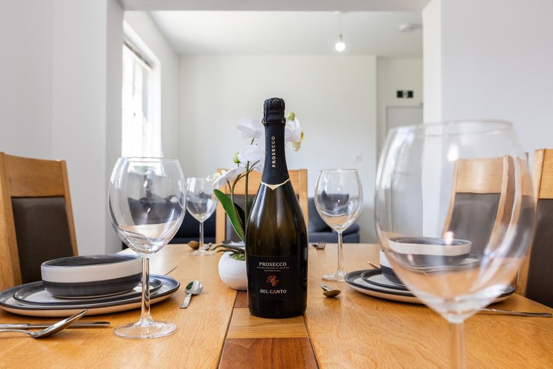 Dining table set with wine glasses, plates, cutlery and champagne bottle