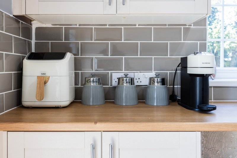Kitchen countertop with white toaster, coffee maker, and storage canisters against grey subway tile backsplash