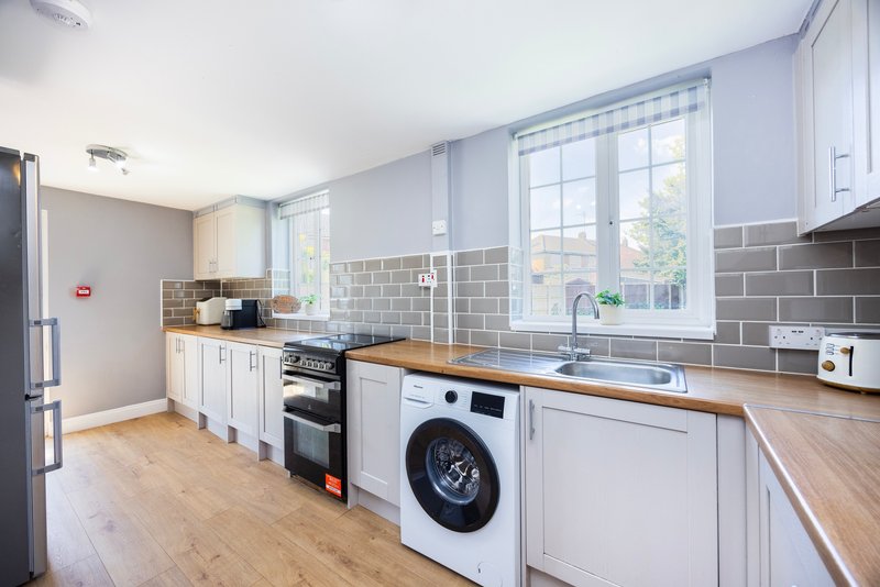 Modern kitchen with white cabinetry, wooden countertops, stainless steel appliances and grey tile backsplash