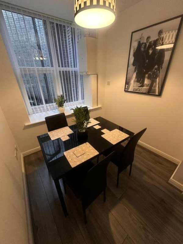 Dining area with black table, chairs, pendant light, window and framed wall art