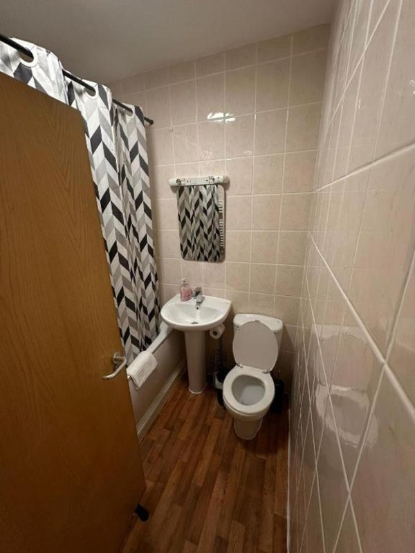 Bathroom with toilet, sink, tiled walls, patterned shower curtain and towel