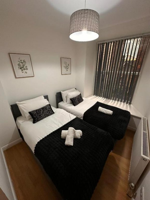 Twin bedroom with white beds, black throws, patterned cushions and pendant light