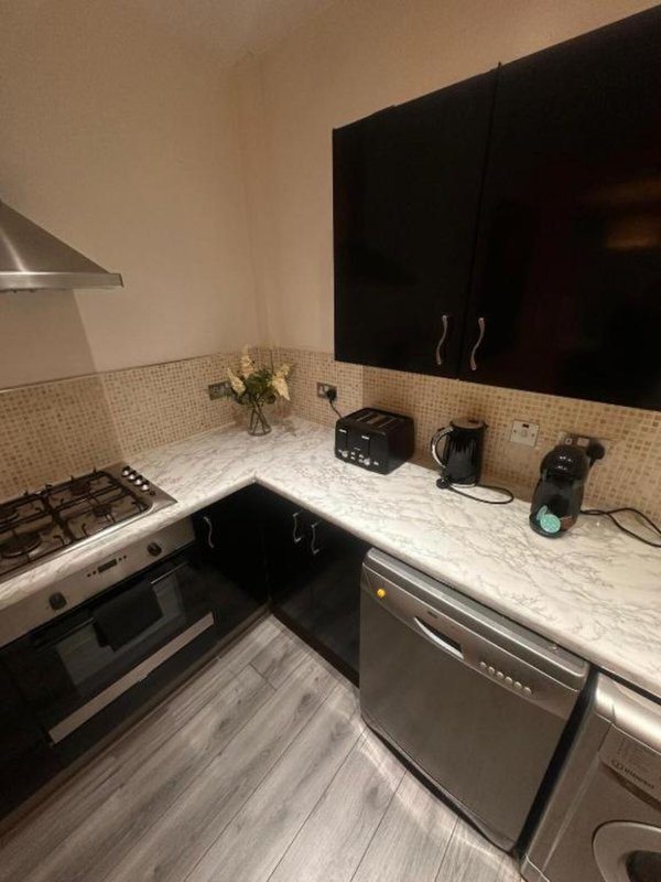 Modern kitchen with black cabinets, white marble countertop, gas hob and stainless steel appliances