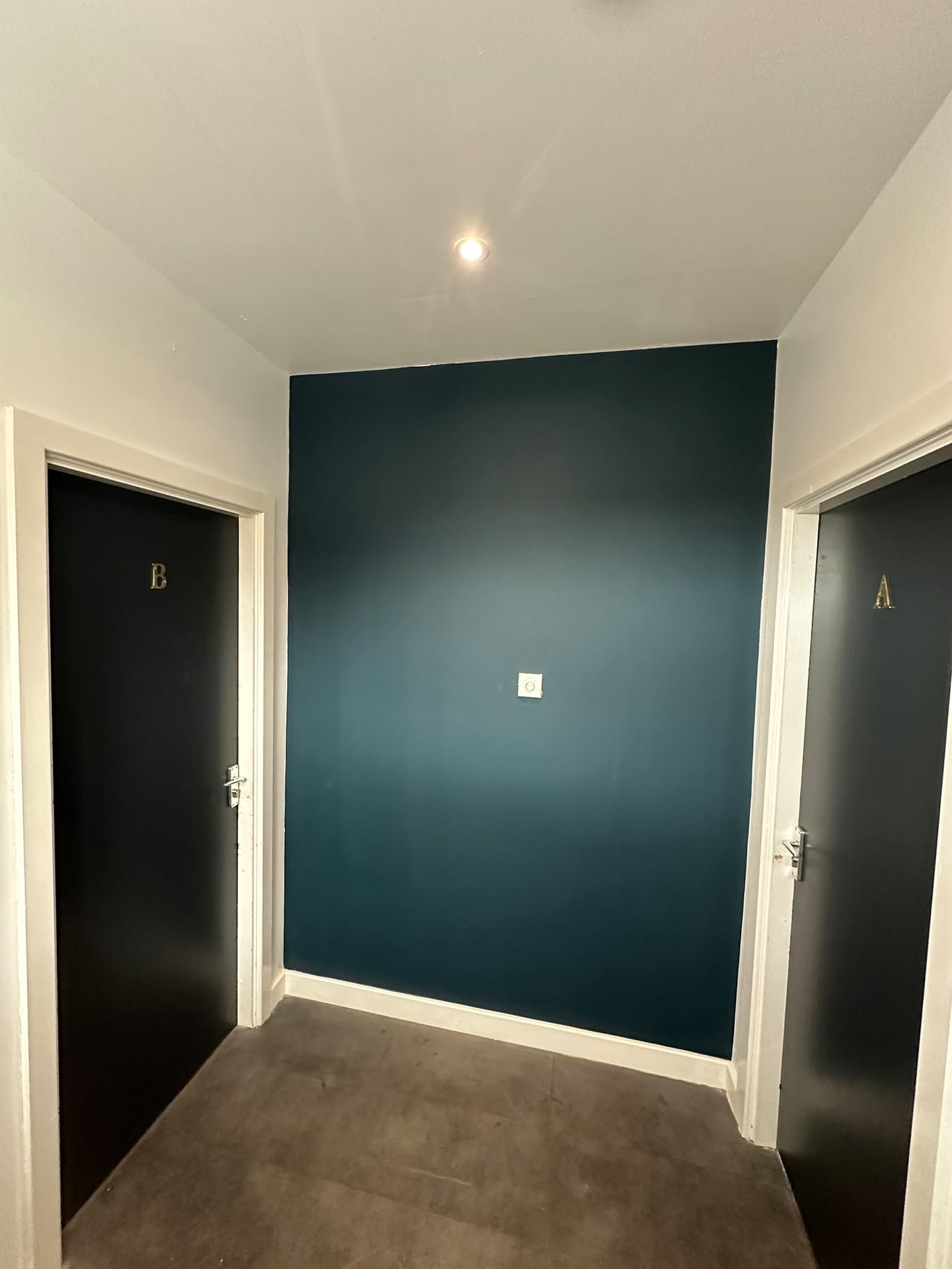 Hallway with teal accent wall, two dark doors labeled A and B, light flooring